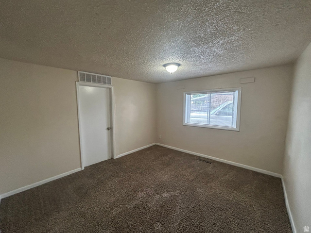 265 Rigdon Avenue, Unit 1 Salt Lake City, UT 84115 - Photo 14 of 15 Carpeted room featuring a white door with a louvered transom, a window with white trim, and a ceiling-mounted light fixture