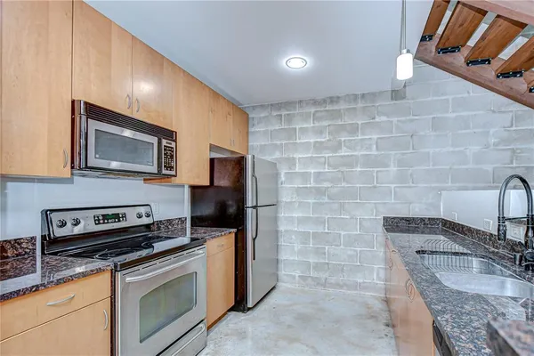 a kitchen with stainless steel appliances granite countertop a stove a refrigerator and a sink with wooden floor