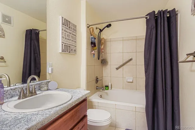 a bathroom with a granite countertop sink toilet and shower