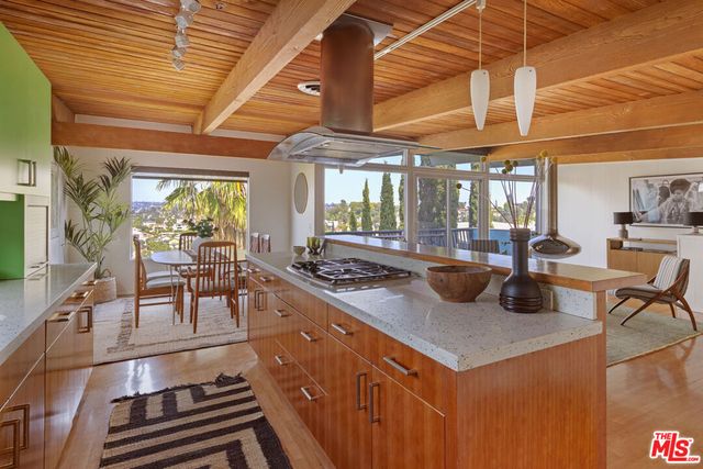 a kitchen with stainless steel appliances granite countertop a stove a refrigerator a dining table and chairs with wooden floor