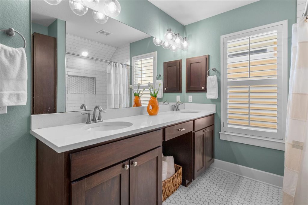 12200 Tawny Farms Road, Unit 139 Austin, TX 78748 - Photo 18 of 30 The primary ensuite is stunning! You get a double vanity with crisp white countertops and deep espresso cabinets that match the kitchen. The vintage-style globe light fixtures give it a fun, modern touch, and the white hex tile flooring feels incredibly fresh.