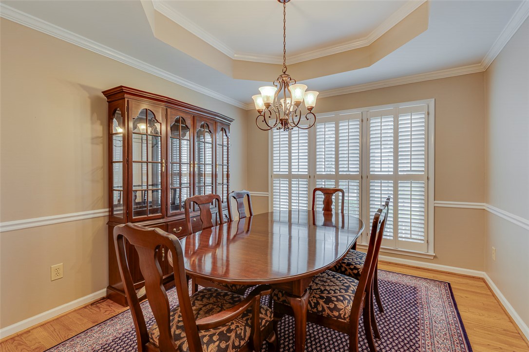 302 Wild Rice Drive Simpsonville, SC 29681 - Photo 19 of 44 A refined dining room showcases warm wood flooring and an elegant tray ceiling layout.