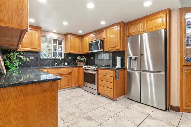 a kitchen with stainless steel appliances granite countertop a refrigerator a sink and a stove