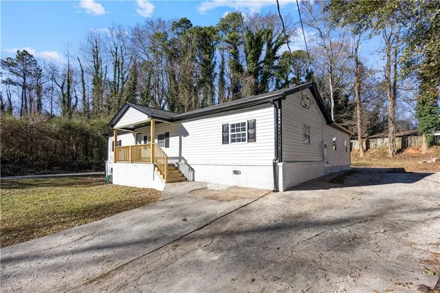 a view of a white house with a yard and large tree