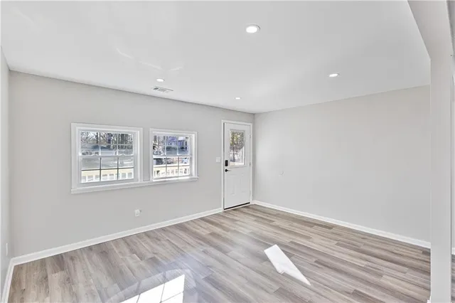 an empty room with wooden floor and windows
