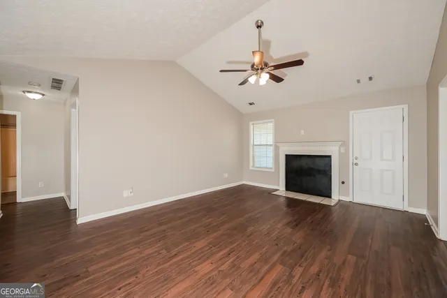 an empty room with wooden floor fireplace and windows