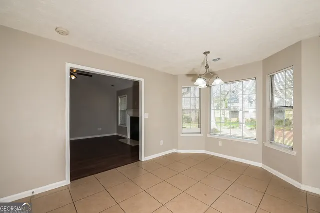 a view of an empty room with window and chandelier fan
