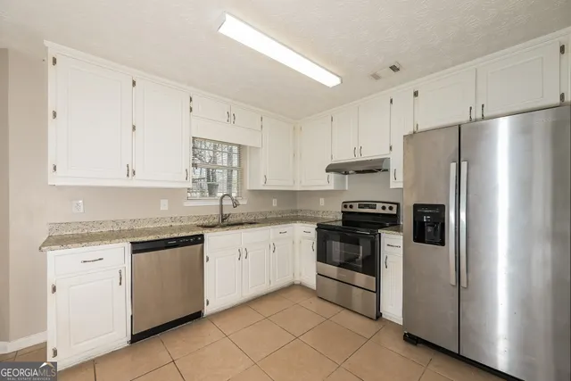 a kitchen with granite countertop white cabinets and stainless steel appliances