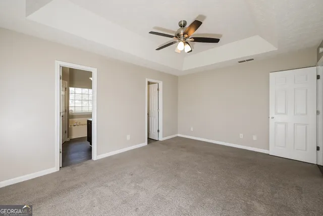 a view of an empty room with closet and a ceiling fan