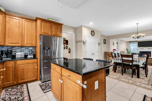 a kitchen with stainless steel appliances granite countertop a refrigerator a sink dishwasher a dining table and chairs with wooden floor