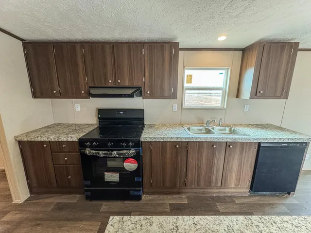 a kitchen with granite countertop a stove a sink and a microwave