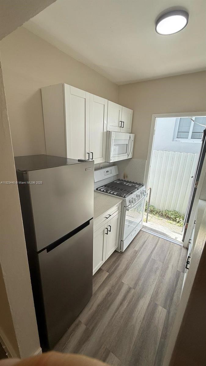 8132 Harding Avenue, Unit 2 Miami Beach, FL 33141 - Photo 14 of 20 a kitchen with granite countertop a refrigerator a sink a stove and white cabinets