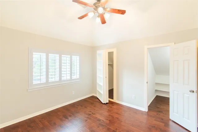 an empty room with wooden floor closet and windows