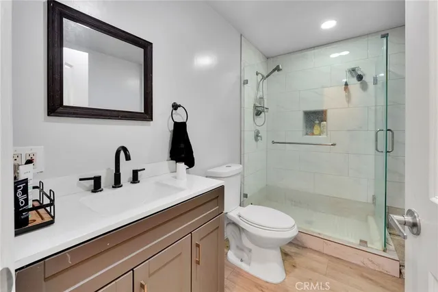 a bathroom with a shower sink vanity mirror and toilet