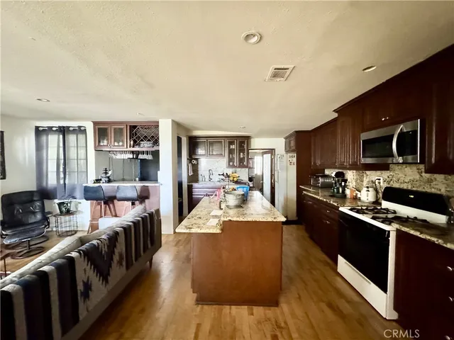a large kitchen with stainless steel appliances and a view of living room