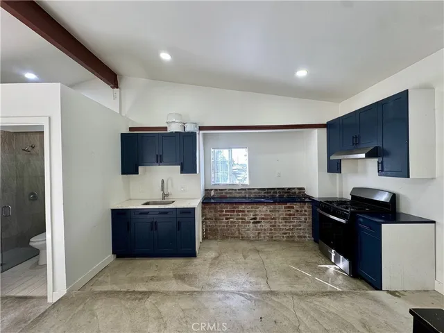 a large kitchen with kitchen island granite countertop a sink and a stove top oven