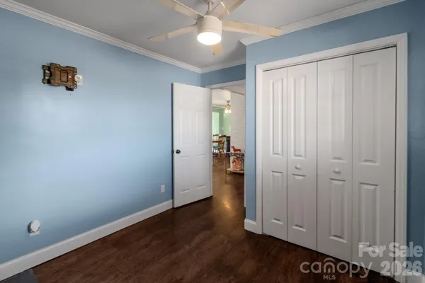 an empty room with wooden floor closet and windows