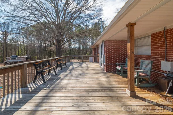 a view of a deck with wooden floor and fence with a bench