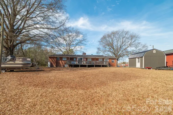 a view of dirt yard with a bench and trees around