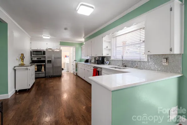 a kitchen with stainless steel appliances a sink dishwasher a stove a refrigerator with wooden floor and cabinets