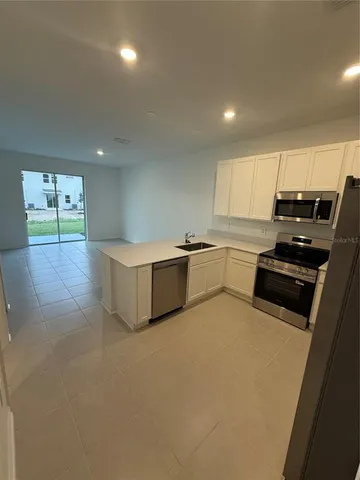 a kitchen with stainless steel appliances a stove a sink a microwave a refrigerator a counter top space and cabinets