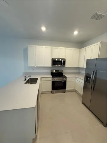 a kitchen with a refrigerator a stove top oven and white cabinets