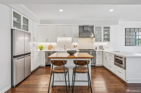 a kitchen with a refrigerator a stove a sink and white cabinets with wooden floor