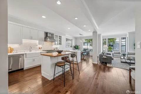 a open dining room with kitchen island stainless steel appliances wooden floor and a refrigerator