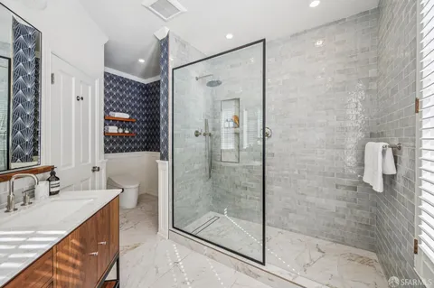 a bathroom with a granite countertop sink a mirror and shower