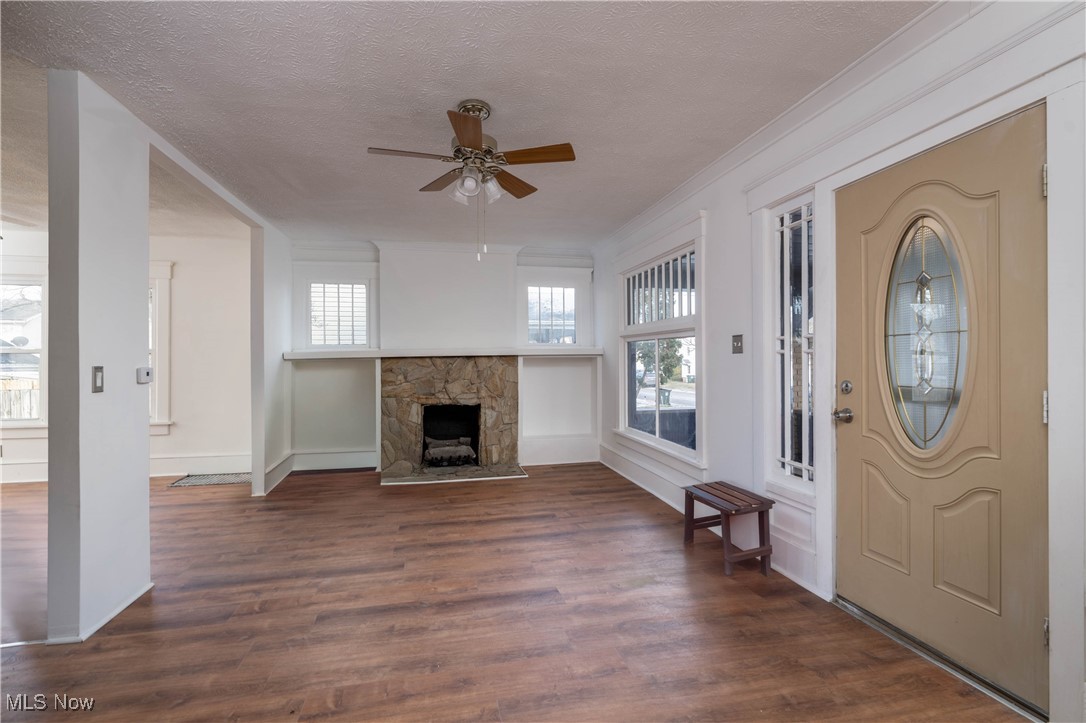 2700 9th Street Northwest Canton, OH 44708 - Photo 14 of 33 Entrance foyer with ceiling fan, a stone fireplace, dark hardwood / wood-style flooring, crown molding, and a textured ceiling