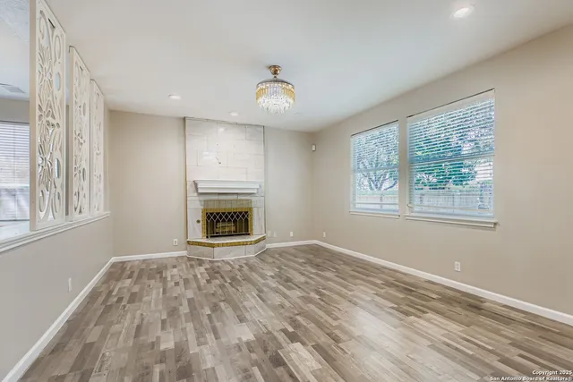 a view of an empty room with a window and wooden floor