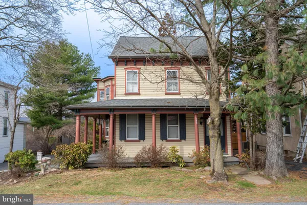 a front view of a house with a garden and trees