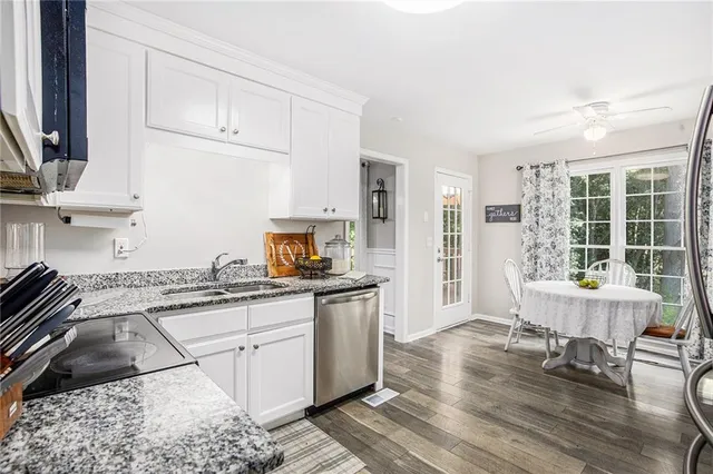 a kitchen with granite countertop a stove a sink a dining table and chairs