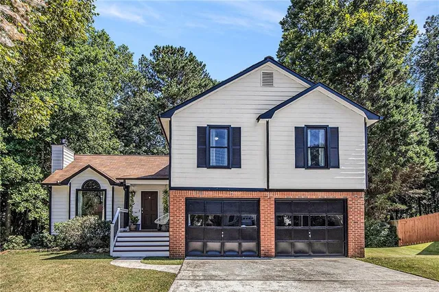 a view of a house with a yard and large tree