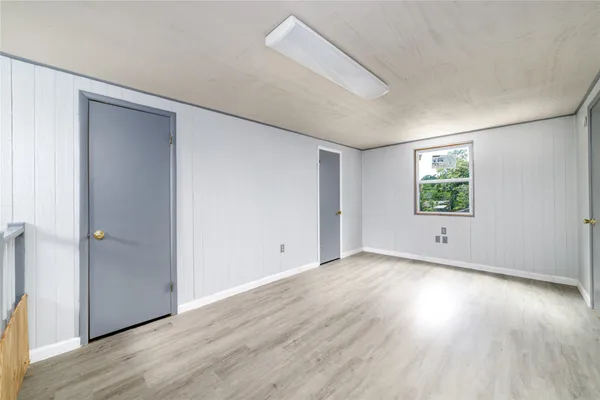 an empty room with wooden floor windows and closet