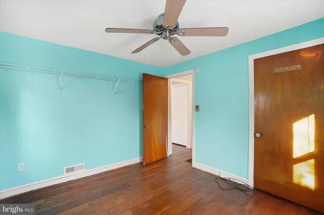 an empty room with wooden floor fan and windows