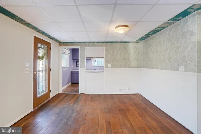 a view of a kitchen with a fridge and wooden floor