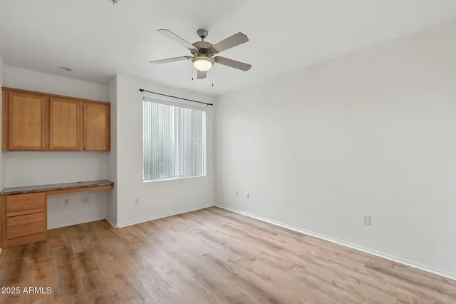 an empty room with wooden floor fan and windows