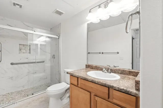 a bathroom with a granite countertop sink toilet mirror and shower