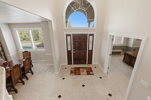 11943 Autumn Ridge Drive East Sandy, UT 84092 - Photo 4 of 59 Entryway featuring a high ceiling, a chandelier, healthy amount of natural light, and light tile patterned floors