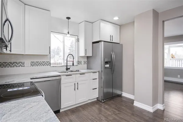 a kitchen with stainless steel appliances a sink cabinets and a wooden floor
