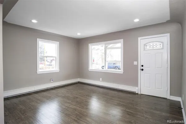 an empty room with wooden floor and windows