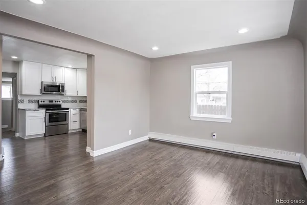 an empty room with wooden floor and stainless steel appliances