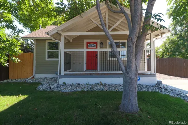a view of a house with a small yard and a large tree