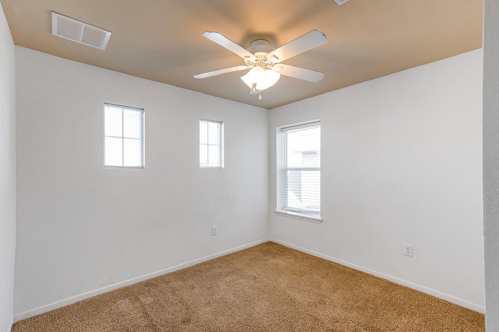 12105 Greywacke Drive Manor, TX 78653 - Photo 12 of 18 an empty room with windows and chandelier fan