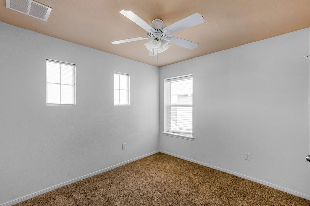 12105 Greywacke Drive Manor, TX 78653 - Photo 15 of 18 an empty room with a ceiling fan and windows