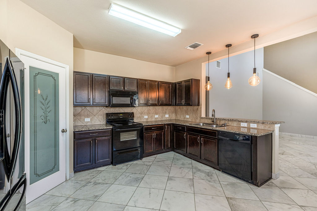 12105 Greywacke Drive Manor, TX 78653 - Photo 8 of 18 a kitchen with stainless steel appliances granite countertop a stove refrigerator and a sink