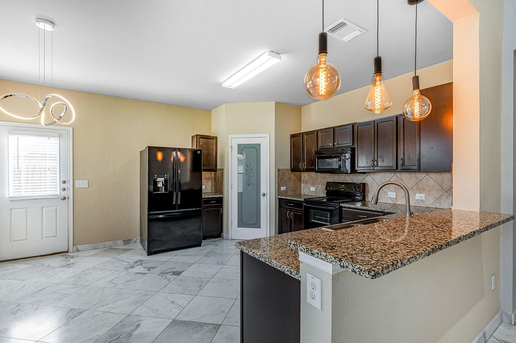 12105 Greywacke Drive Manor, TX 78653 - Photo 9 of 18 a kitchen with stainless steel appliances granite countertop a sink refrigerator and microwave