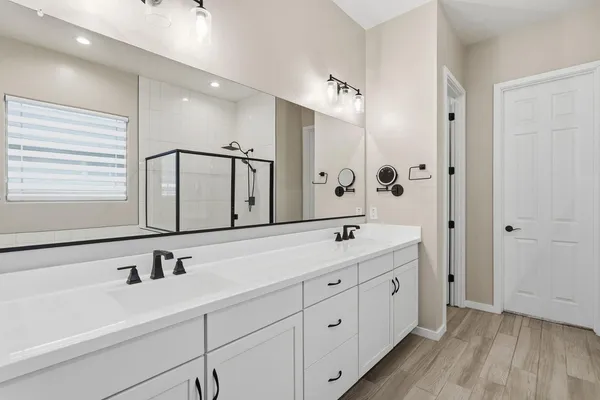 a spacious bathroom with a double vanity sink a mirror and shower