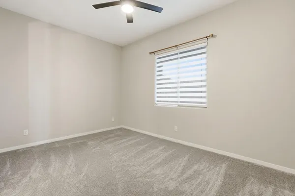 an empty room with a window and a ceiling fan